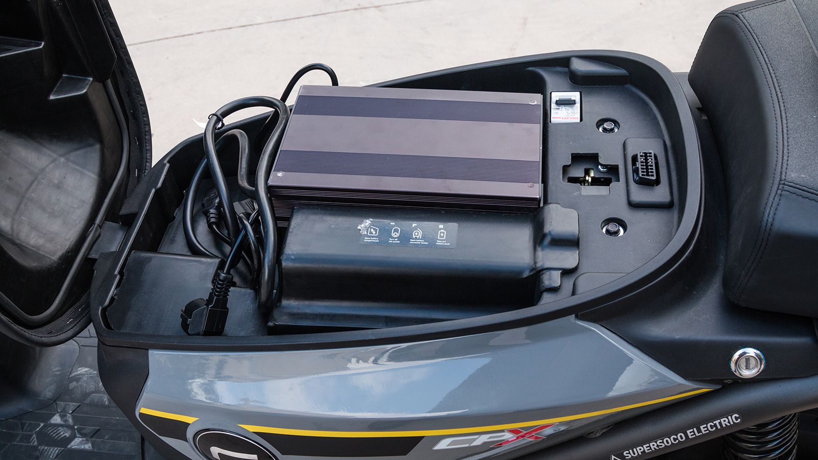 Κάτω από τη σέλα δεν υπάρχει ο παραδοσιακός χώρος για τοποθέτηση αντικειμένων. Αντί αυτού θα συναντήσουμε ένα φορητό φορτιστή, και κάτω από το πλαστικ