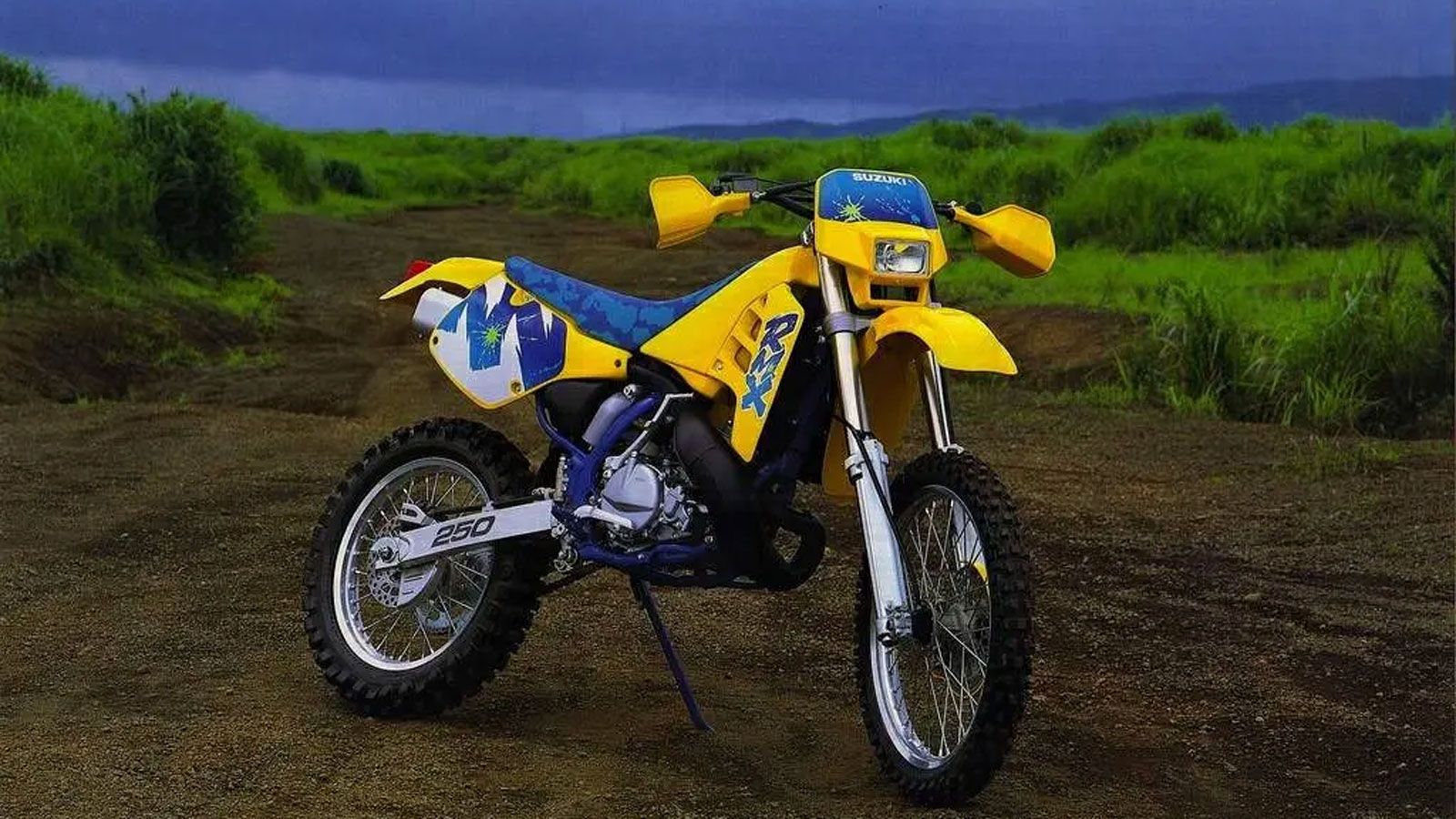 Στα 90s, η Suzuki RMX250S έμοιαζε λες και βγήκε κατευθείαν από το parc fermé ενός αγώνα enduro. Προερχόταν από την αγωνιστική RMX250, που είχε ρί