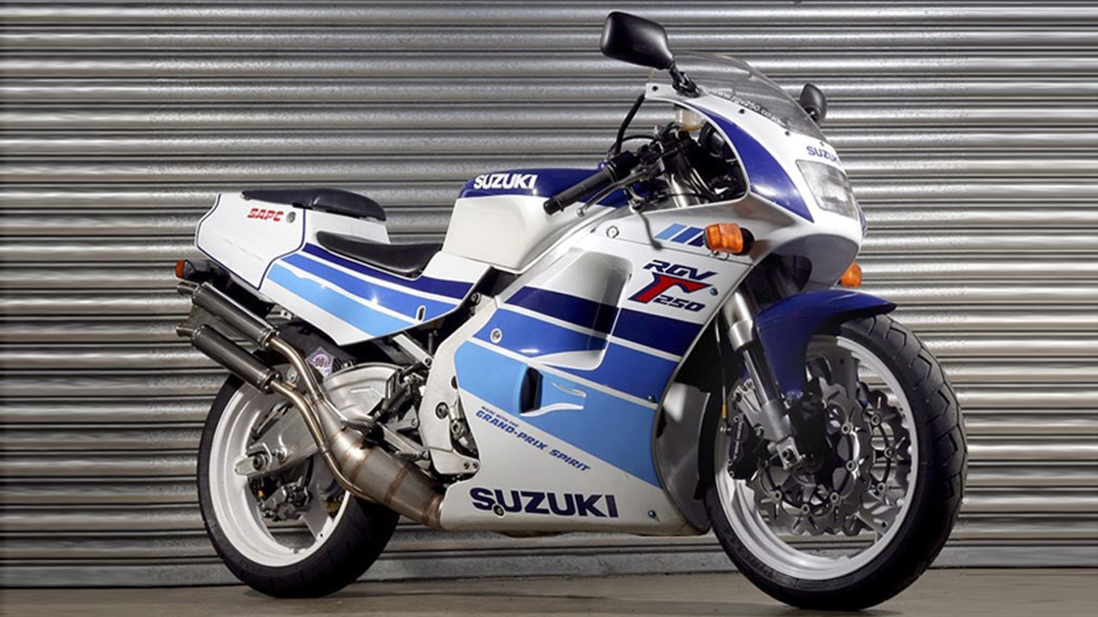 ο Suzuki RGV 250 “Banana”, με την εμβληματική διχρωμία, το δίχρονο ουρλιαχτό του και το φιδίσιο ψαλίδι που έμοιαζε να βγήκε από το μέλλον,