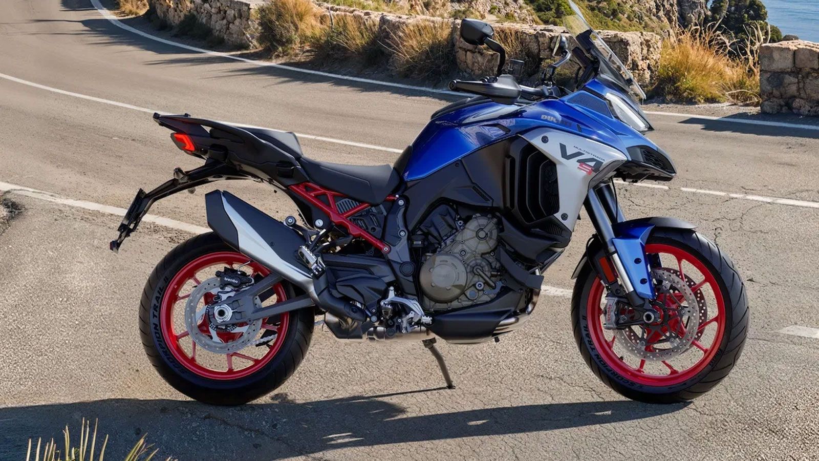 Ducati Multistrada V4 σε μπλε χρωματισμό με κόκκινες ζάντες σταθμευμένη σε ορεινό δρόμο, αναδεικνύοντας το νέο πρόγραμμα εξατομίκευσης Ducati Factory 