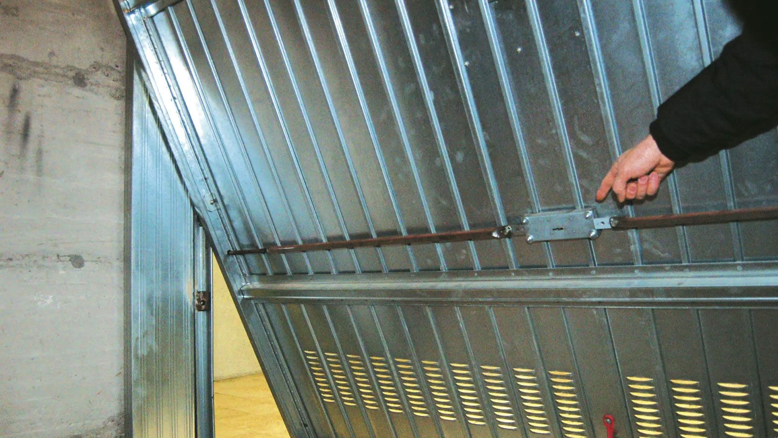 Εσωτερική πλευρά πόρτας γκαράζ με μεταλλική μπάρα ασφάλειας, που ενισχύει την προστασία από παραβίαση.